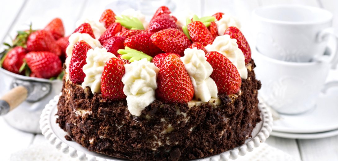 Efektowny tort z bitą śmietaną i truskawkami. Idealny na wykwintne przyjęcie